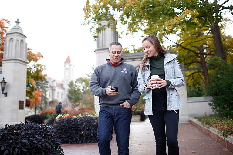 A student and her father look at a mobile phone.